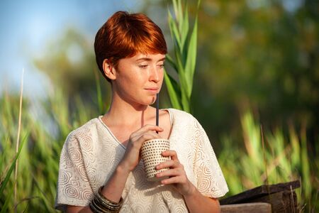 WOMAN DRINKING STRAW IN THE COUNTRYSIDEの写真素材