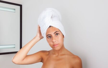 Portrait of a beautiful young woman eurasian in a bathroom. Youthful girl with perfect skin using...