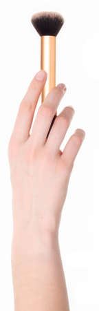A woman's hand holding a makeup brush.