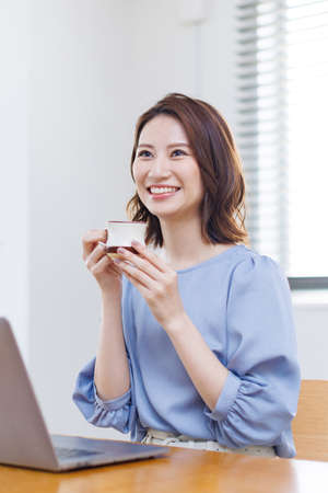Young Asian woman smiling and holding a mugの写真素材