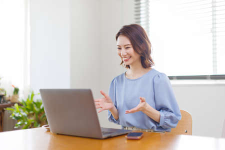 Young Asian woman having a video call on a laptopの写真素材
