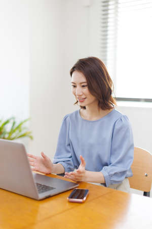 Young Asian woman having a video call on a laptopの写真素材