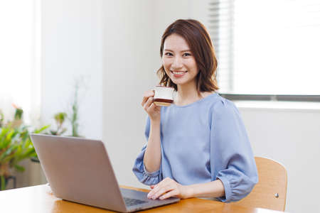 Young Asian woman smiling and holding a mugの写真素材