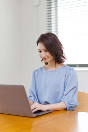Young Asian woman in casual clothing using a laptopの写真素材