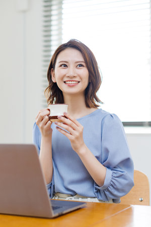 Young Asian woman smiling and holding a mugの写真素材