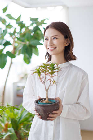 Young Asian woman holding a plantの写真素材