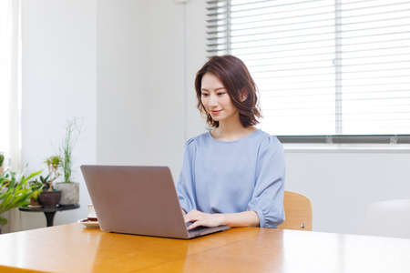 Young Asian woman in casual clothing using a laptopの写真素材