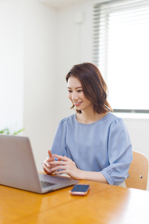 Young Asian woman having a video call on a laptopの写真素材