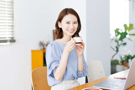 Young Asian woman smiling and holding a mugの写真素材