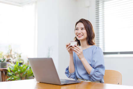 Young Asian woman smiling and holding a mugの写真素材