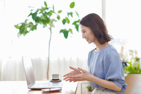 Young Asian woman having a video call on a laptopの写真素材