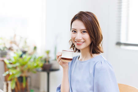 Young Asian woman smiling and holding a mugの写真素材