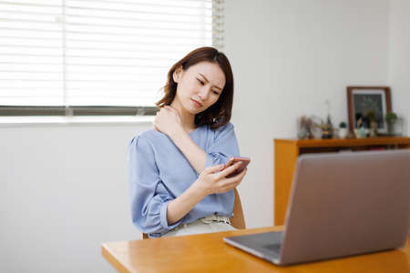 Young Asian woman having shoulder painの写真素材