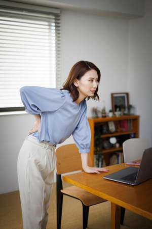Young Asian woman having waist painの写真素材