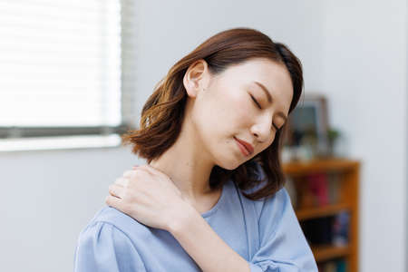 Young Asian woman having shoulder painの写真素材