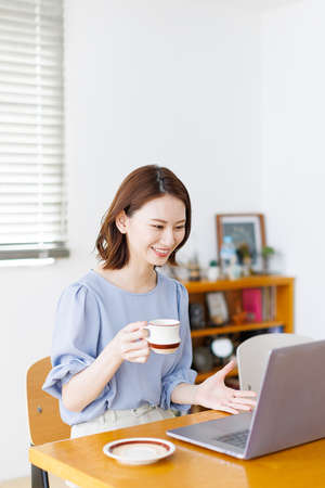Young Asian woman having a video call on a laptopの写真素材