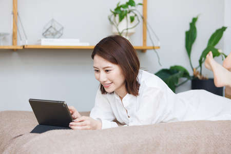 Young Asian woman watching at her tablet computerの写真素材