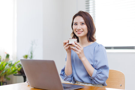 Young Asian woman smiling and holding a mugの写真素材