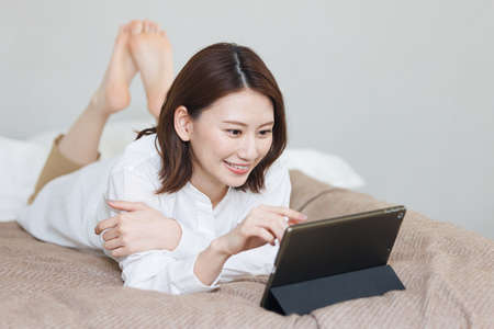 Young Asian woman watching at her tablet computerの写真素材