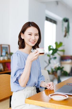 Young Asian woman smiling and holding a mugの写真素材