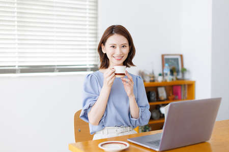 Young Asian woman smiling and holding a mugの写真素材