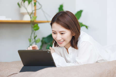 Young Asian woman watching at her tablet computerの写真素材