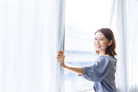 Young Asian woman standing by a windowの写真素材