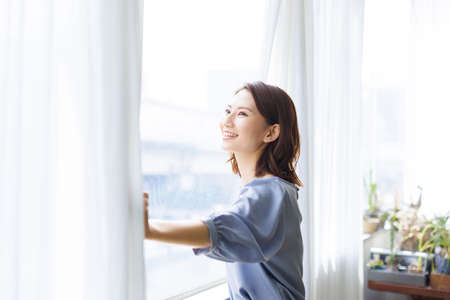 Young Asian woman looking out from the windowの写真素材
