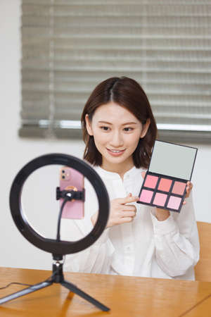 Young Asian woman live streaming with cosmeticの写真素材