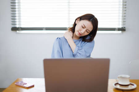 Young Asian woman having shoulder painの写真素材