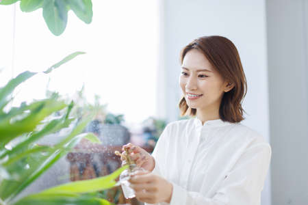 Young Asian woman spraying water on the plantの写真素材