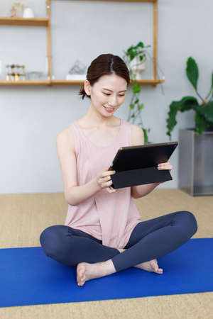 Young Asian woman watching workout video on tablet computerの写真素材