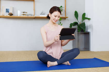 Young Asian woman watching workout video on tablet computerの写真素材