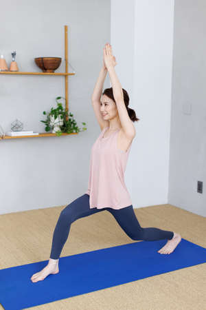Young Asian woman practicing yoga at homeの写真素材