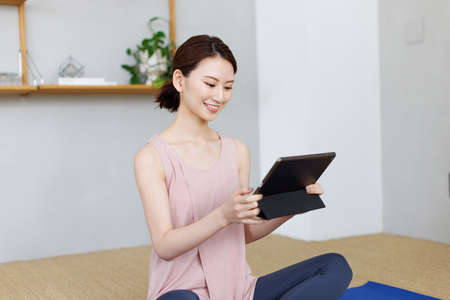 Young Asian woman watching workout video on tablet computerの写真素材