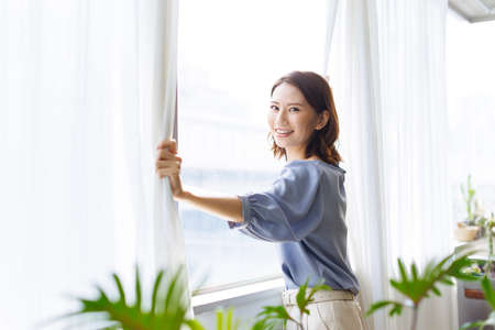Young Asian woman standing by a windowの写真素材