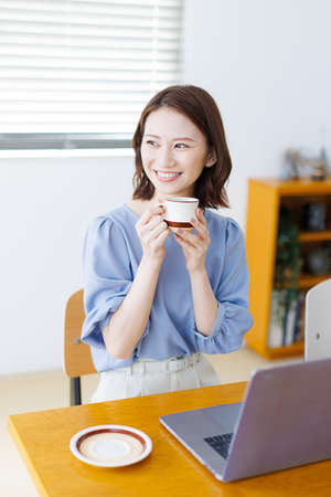 Young Asian woman smiling and holding a mugの写真素材