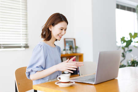 Young Asian woman having a video call on a laptopの写真素材