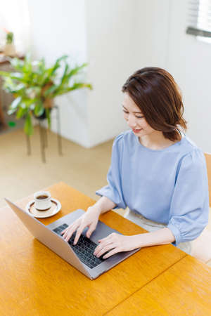 Young Asian woman using a laptop and smilingの写真素材