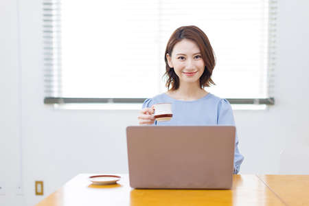 Young Asian woman smiling and holding a mugの写真素材
