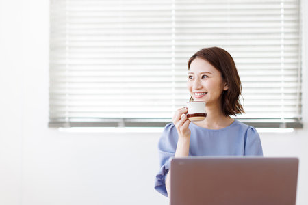 Young Asian woman smiling and holding a mugの写真素材