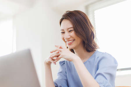 Young Asian woman having a video call on a laptopの写真素材
