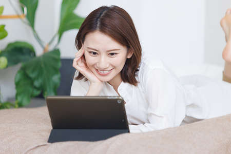 Young Asian woman watching at her tablet computerの写真素材