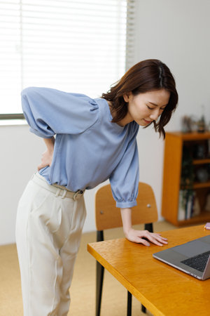 Young Asian woman having waist painの写真素材