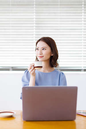 Young Asian woman smiling and holding a mugの写真素材