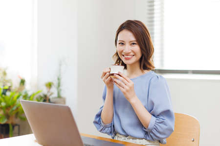 Young Asian woman smiling and holding a mugの写真素材
