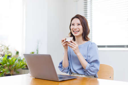 Young Asian woman smiling and holding a mugの写真素材