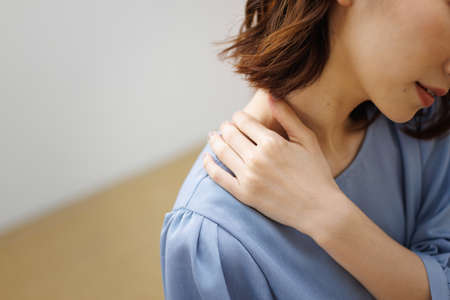 Young Asian woman having shoulder painの写真素材