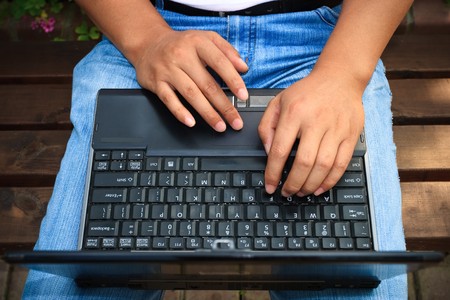 man using laptop on a bench in the park outdoor.