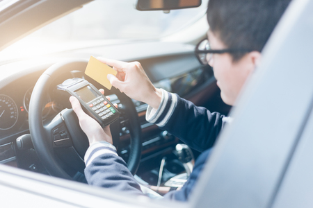 man in a car swiping credit card on wireless POS machineの写真素材